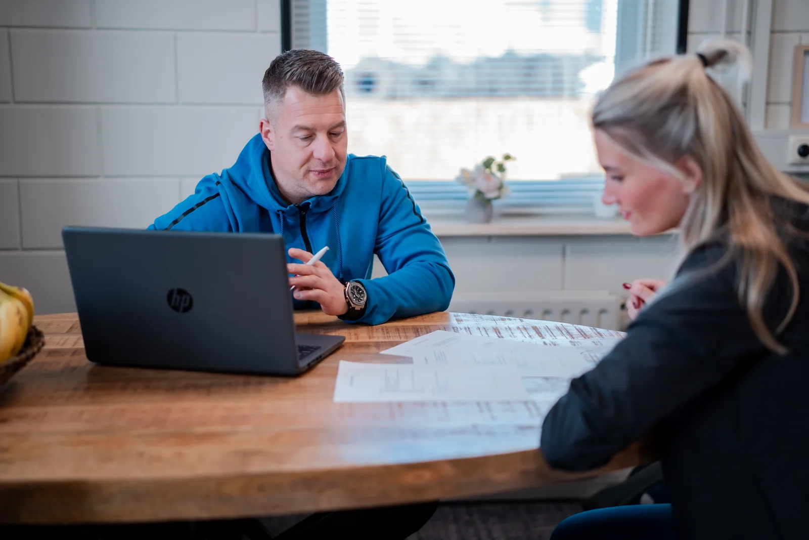 Arnold Luitjes aan tafel in gesprek, met uitslagen voor zich